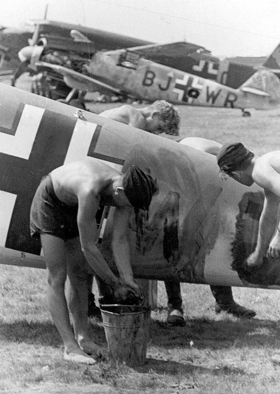 Un soldato, intento nella rimozione degli Stammkennzeichen da un Me Bf 109. Sullo sfondo, un altro aereo simile con i codici ancora presenti.
